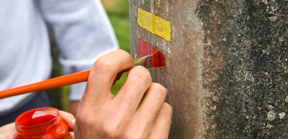 main qui peint une balise